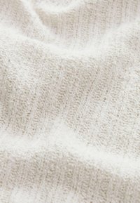 Biała dzianina z textured wzorem, z wypukłymi paskami i miękkim wyglądem, odpowiednia do odzieży lub tekstyliów domowych.