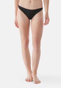Zwarte bikini slipjes met een lage taille, een gladde stoftextuur en minimale bedekking, getoond op een staande figuur.