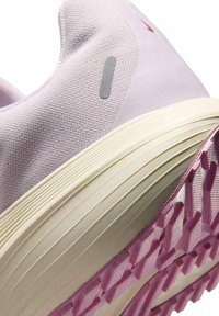 Close-up of a light purple athletic shoe heel with textured fabric, cream midsole with horizontal grooves, and pink patterned outsole.