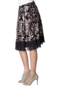 Plisseret midi nederdel i sort, beige og hvidt abstrakt mønster; letvægtsstof med en gennemsigtig sort kant. Kombineres med åbne, snørestøvler med hæl.
