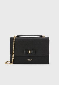 Borsa nera con texture, dotata di una tracolla in catena dorata, con un dettaglio a fiocco e il logo sulla parte anteriore. Chiusura magnetica nella parte superiore.