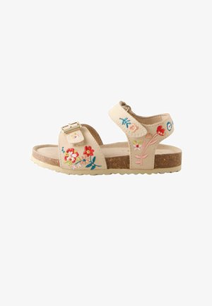 Sandale beige pour enfants avec semelle en liège, brides à la cheville et sur les orteils, fleurs colorées brodées et fermeture à boucle dorée sur la bride des orteils.