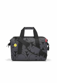 Borsa da viaggio in tessuto grigio con motivo a faccina sorridente nera, manici in webbing neri, tracolla regolabile e dettaglio di portachiavi a faccina sorridente gialla.