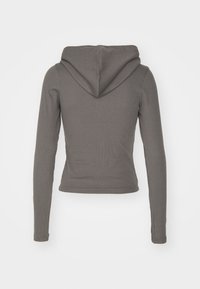 Sweat à capuche gris à manches longues avec une texture côtelée, présentant une capuche arrondie et une silhouette ajustée. Aucun fermoir ou motif visible.
