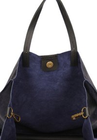 Grote tote bag van zachte marineblauwe suède, zwarte leren handvatten en een messing drukknoopsluiting. Inclusief interieurhardware en ritsclips.