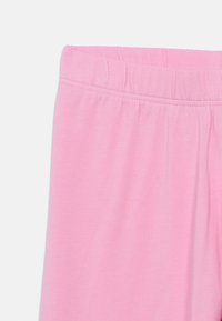 Ανοιχτό ροζ βαμβακερό παντελόνι με ελαστική μέση, με ομαλή υφή και απλό σχέδιο. Δεν υπάρχουν επιπλέον σχέδια ή διακοσμητικά στοιχεία ορατά.