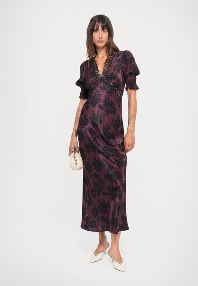 Purple satin dress with floral pattern, V-neck, lace accents, short puff sleeves, and a straight silhouette. Model holds a small white purse.