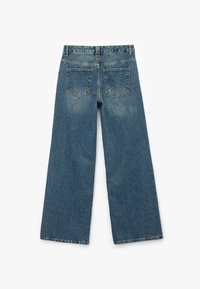 Pantalones de mezclilla de pierna ancha vistos desde atrás, con dos bolsillos traseros, pasadores para cinturón y un lavado azul desteñido.