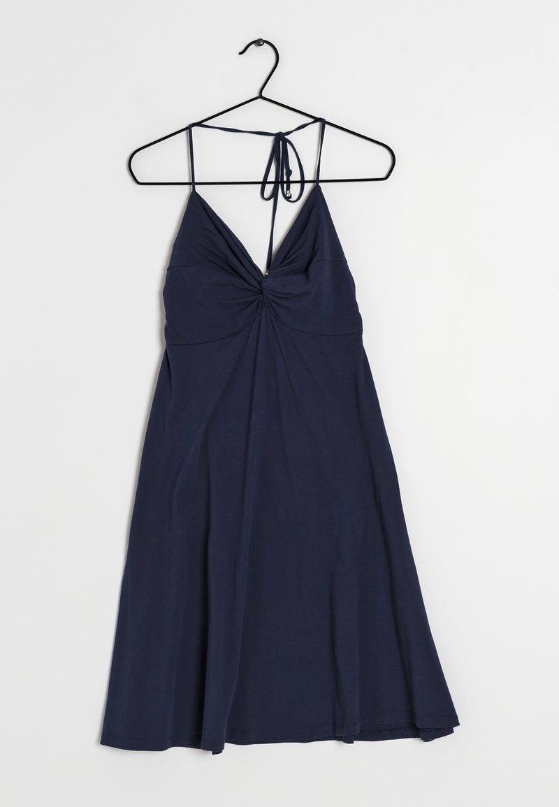 Mörkblå ärmlös klänning med spaghettistilar och rynkodetalj vid bröstet, hängande på en svart galge mot en vit bakgrund.