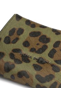 Zielony portfel w zwierzęcy wzór z czarnymi plamami, wykonany z teksturowanego materiału. Posiada wytłoczone logo "ALMA EN PENA" na dolnej krawędzi.