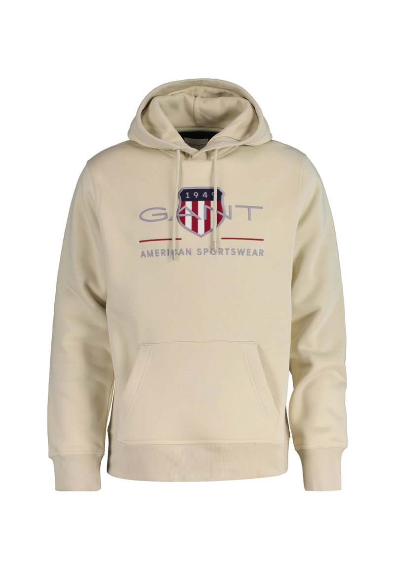 Crème-kleurige hoodie gemaakt van zachte stof. Bevat een voorzak, een capuchon met trekkoord en een grafisch logo met rode, marineblauwe en grijze accenten.