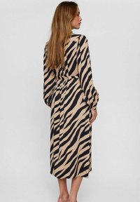 Rochie bej cu dungi negre de zebra, cu mânecă lungă și lungime medie, având talie strânsă și textură moale a materialului.