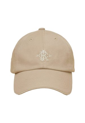 Beige baseballkasket med buet skygge, ventilationshuller og hvidt broderet logo med teksten "1989" og styliserede bogstaver foran i midten.