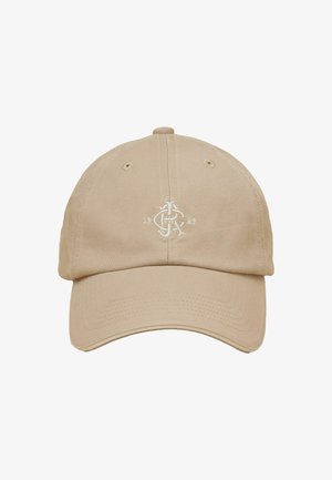 Beige baseballkasket med buet skygge, ventilationshuller og hvidt broderet logo med teksten "1989" og styliserede bogstaver foran i midten.
