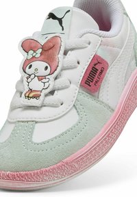 Baskets pour jeunes présentant une tige en cuir blanc, des accents en suède vert et une semelle en caoutchouc rose, avec un personnage My Melody sur la languette.