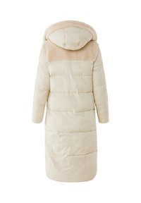 Lång, vadderad kappa i ljusbeige med en mjuk beige pälsfäll. Har huva och rak fåll, designad med quiltsöm.