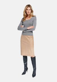 Szaro-ribbed top z długim rękawem zestawiony z beżową skórzaną spódnicą ołówkową. Dopełniająca stylizację czarne kozaki do kolan na obcasie. Gładkie struktury i dopasowana sylwetka.