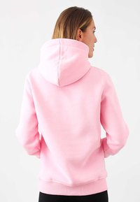 Hoodie rosa con un ampio cappuccio morbido, polsini e orlo a coste, realizzato in tessuto testurizzato, caratterizzato da una vestibilità rilassata e un design semplice.