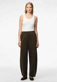 Pantalons larges vert foncé avec une taille élastique, associés à un débardeur blanc ajusté. Le tissu semble doux et confortable.