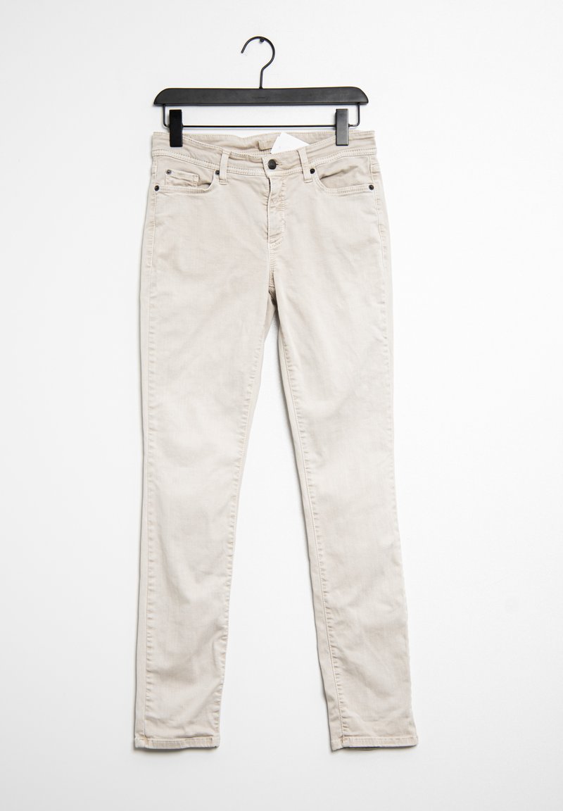 Jeans beige colgados de una percha negra. Incluye cinco bolsillos, una cremallera y una textura sutil en la tela de algodón.