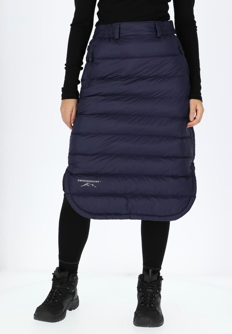 Laivastonsininen puffihame, jossa on vaakasuora tikkauskuvio, puolipitkä, sivuvetoketjut ja logo helman kohdalla. Yhdistetty mustien leggingsien ja saappaiden kanssa.