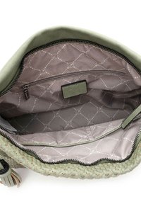 Wewnętrzna część plecionej zielonej torby z miękką szaro-skalną podszewką w diamentowy wzór, kieszenią na zamek i małą metką. Teksturowany materiał.