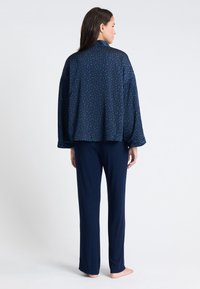 Granatowy zestaw odzieży domowej z wzorzystą, oversize'ową bluzą z długimi rękawami oraz pasującymi prostymi spodniami, wykonany z miękkiego materiału.