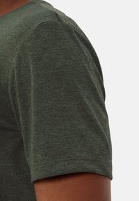 T-shirt verde a maniche corte con tessuto texture, scollatura rotonda e un logo sottile sulla manica sinistra.