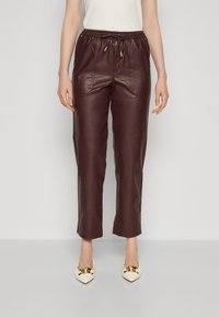 Bordowe joggery ze skóry z elastycznym paskiem w talii, sznurkiem i przednimi kieszeniami, o gładkiej fakturze i skróconym kroju.