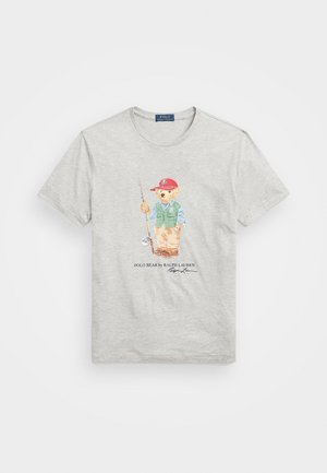Lichtgrijs T-shirt met een bedrukt beeld van een beer die een rode pet, een groen vest draagt, een hengel vasthoudt, met de tekst "Polo Bear by Ralph Lauren."