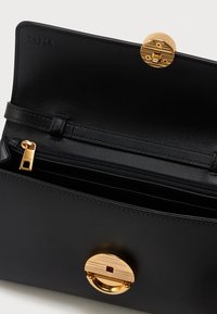 Fekete b�őr Furla pénztárca nyitva, arany zipzárral, több rekesszel és kerek arany zárócsattal a fedélen.