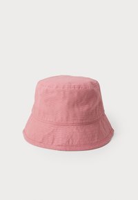 Chapéu rosa em forma de balde, feito de tecido texturizado, com uma aba larga e uma coroa arredondada. Design simples, sem padrões ou acessórios adicionais.