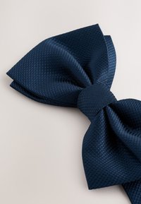 Papillon blu navy in tessuto strutturato, caratterizzato da un grande fiocco a strati con un nodo centrale liscio.