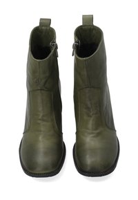 Pár olivově zelených kožených kotníkových bot se čtveratými špičkami, bočními zipy a černými podrážkami, zobrazených čelně na bílém pozadí.