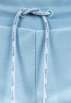 Pantaloni jogger azzurro chiaro con cintura a costine, dotati di un cordoncino con testo stampato. Tessuto morbido e vestibilità sartoriale.