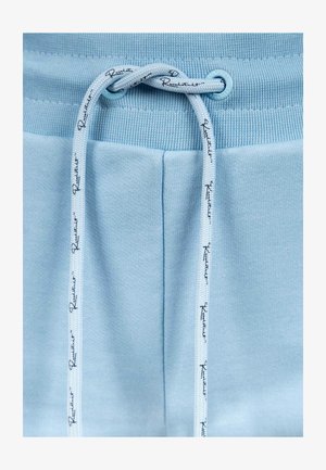 Pantaloni jogger azzurro chiaro con cintura a costine, dotati di un cordoncino con testo stampato. Tessuto morbido e vestibilità sartoriale.