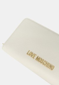 Portafoglio bianco con texture, caratterizzato da un logo dorato "LOVE MOSCHINO" ben visibile sulla parte anteriore. Forma rettangolare con angoli arrotondati.