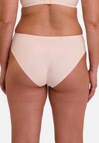 Bas de bikini rose clair sans couture avec une taille mi-haute et une texture lisse, présentant une coupe classique au niveau des jambes sans quincaillerie ou embellissements visibles.