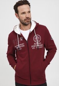 Felpa con zip bordeaux, con cappuccio foderato bianco, caratterizzata da testo e grafiche stampate, tasche frontali e polsini e orlo a coste.
