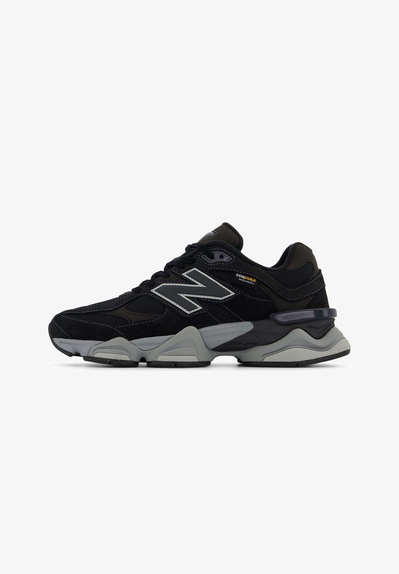 Baskets de sport New Balance noires et grises avec semelle grise, lacets, logo réfléchissant "N" et étiquette en tissu "CORDURA" sur le côté.