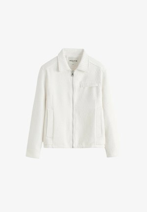 Veste zippée blanche texturée avec col, manches longues, deux poches latérales et une poche à rabat sur la poitrine.