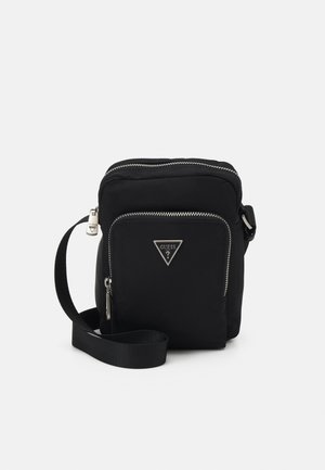 Bolsa cruzada de nylon negra con cierre de cremallera plateada, acento de logo y correa ajustable. Textura suave y forma rectangular compacta.