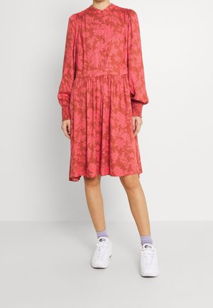 Robe à manches longues, longueur genou en corail avec un motif floral, taille froncée et devant boutonné. Les poignets présentent des détails élastiques.