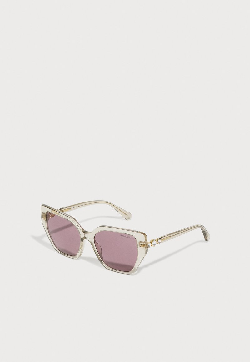 Kissakatse silmadega prillid, millel on läbipaistvad raamid ja lillad objektiivid. Kuldse viimistlusega käed. Nurgeline kuju rõhutab kaasaegset disaini.