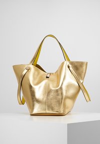 Zlatá metalická taška přes rameno s měkkým, volným designem, která má žluté akcenty na uchu. Obsahuje horní uzávěr a hladký povrch.
