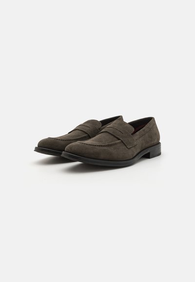 Mocasines de ante gris con un tacón bajo, que presentan un diseño cosido y una doble correa en el empeine. Textura suave y punta redonda.