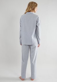 Set di pigiama a righe in cotone blu e bianco. Top con colletto a maniche lunghe e chiusura a bottoni sul retro, abbinato a pantaloni con orli a polsino.