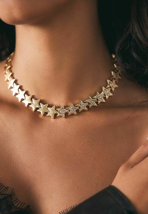 Goldene Choker-Halskette mit abwechselnden sternförmigen Gliedern, wobei einige Sterne von runden, klaren Edelsteinen akzentuiert werden, was einen schimmernden Effekt erzeugt.