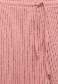 Tissu tricoté côtelé rose avec un cordon noué assorti, montrant la texture et un gros plan de la zone de la taille.