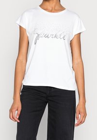 Camiseta de manga corta blanca con un diseño de "brillo" de strass en el frente, hecha de suave material de algodón.
